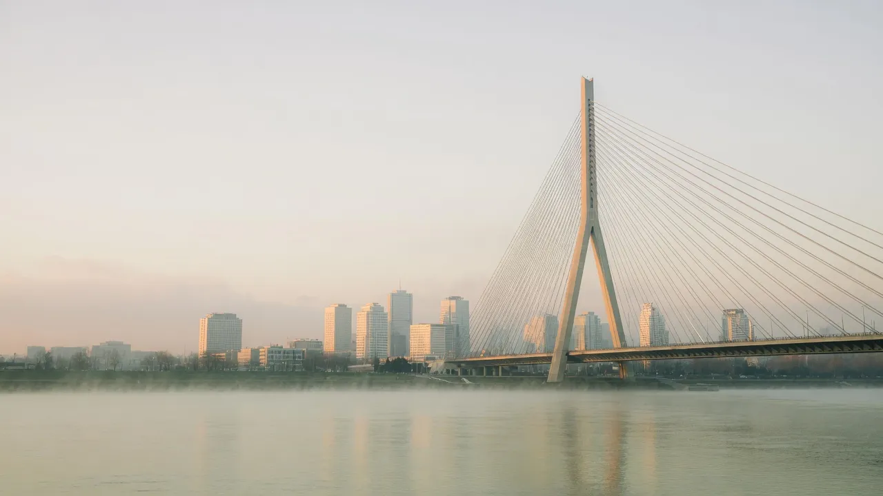 Belgrade at dawn over the Sava River, with the New Belgrade skyline and a cable-stayed bridge